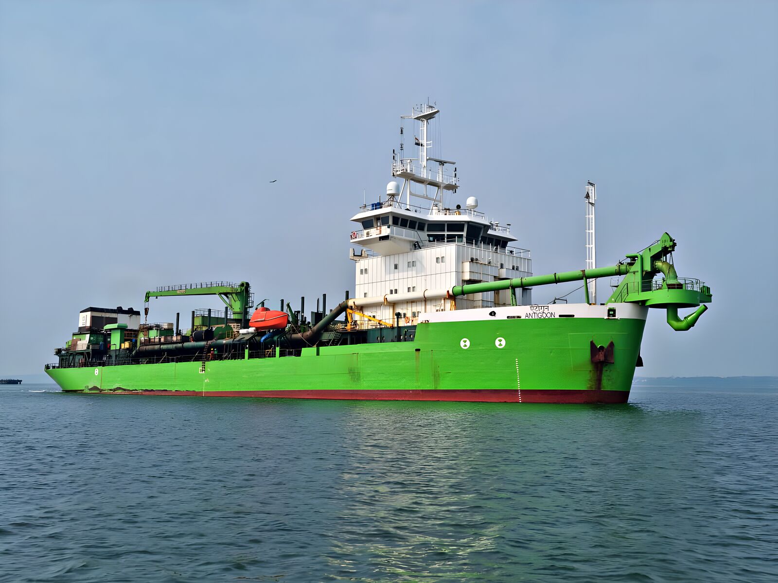 ANTIGOON, a green trailing suction hopper dredger, at sea under a pale sky
